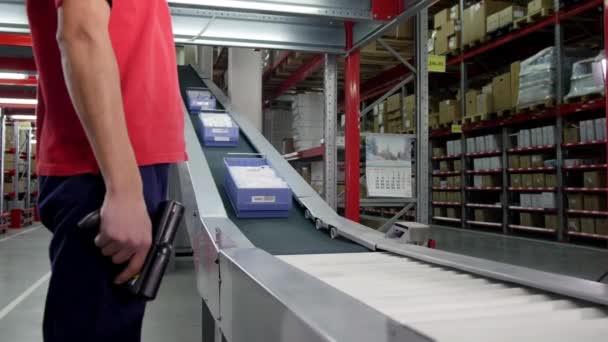 穿着工作服的男性仓库员工在传送带线上工作 并在仓库的盒子中扫描消费品的便携式数据终端条形码 — 图库视频影像