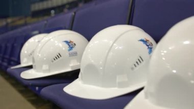 Stadyumun yakın çekimlerindeki izleyicilere beyaz koruyucu miğferler. Spor merkezindeki endüstriyel şirket çalışanlarına yer ayırttım.