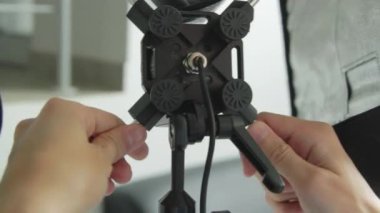 Fotoğrafçı cihazları yerleştirir ve yansıtıcıyı stüdyoya ayarlar. Profesyonel kameraman yakın çekim için ekipman hazırlıyor.