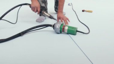 Deneyimli işçiler yüzme havuzu döşeme işlemleri için profesyonel aletler kullanır. Uzman, beyaz malzemeyi yakın çekim ekipmanlarıyla birleştiriyor