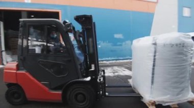 KYIV, UKRAINE - SEPTEMBER 27 2021: Depo yükleyicisi elektrikli forkliftle polikarbonat yapı malzemelerini taşıyor. İşçi taşıma paketi ahşap palet üzerine eğik altında depolama yerine