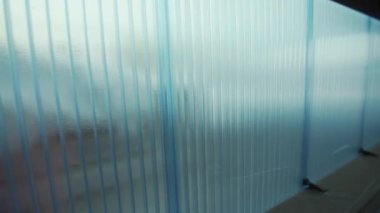 Dikey olarak yerleştirilmiş çokkarbonat panelleri. Açık mavi, ahşap çerçeveli yarı şeffaf duvarlar. İnşaat için modern plastik malzeme