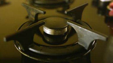 İnsan enerji vermek için lezzetli kahve yapmak için gaz pişirme yüzeyini açar. Ev hanımı gaz sobasının düğmesini çevirir ve kahve makinesi koyar.