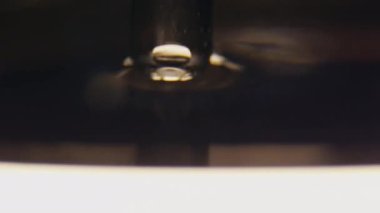 Pipette suya batar ve az miktarda su toplar ve damlacıklar yapar. Damlalar temiz suya düşer ve dalgalar oluşturur makro