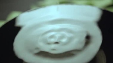 Kase içindeki temiz su, üzerine düşen kalın damlacıklardan sallanıyor. Su damlaları düşer ve yüzeyde küçük daireler çizer.