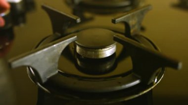 Kişi gaz ocağındaki siyah ocağa kahve makinesi koyar. Kadın bütün gün kendini enerjik hissetmek için gaz pişirme yüzeyinde kahve yapıyor.