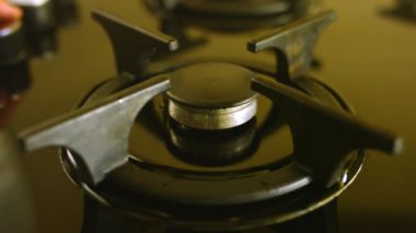 İnsan nefis bir kahve hazırlamak için gaz pişirme yüzeyini açar. Ev hanımı kahve makinesinde içecek yapmak için gaz sobası kullanıyor.
