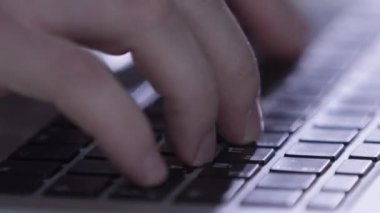 Erkek serbest çalışanın parmakları modern dizüstü bilgisayarın klavyesindeki tuşlara basıyor. Elektronik cihazların kapatılması üzerine bitirilmiş işlerin raporları