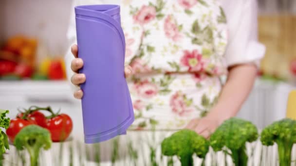 家庭主妇对厨房显示出灵活的切割板 身穿花卉围裙的妇女在蔬菜中展示厨房板 — 图库视频影像