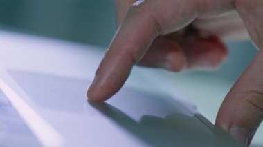 İnsanın parmağı bulanık arka planda modern dizüstü bilgisayarda çalışmak için dokunmatik ped kullanır. Erkek serbest çalışan, evdeki elektronik cihazda çalışıyor.