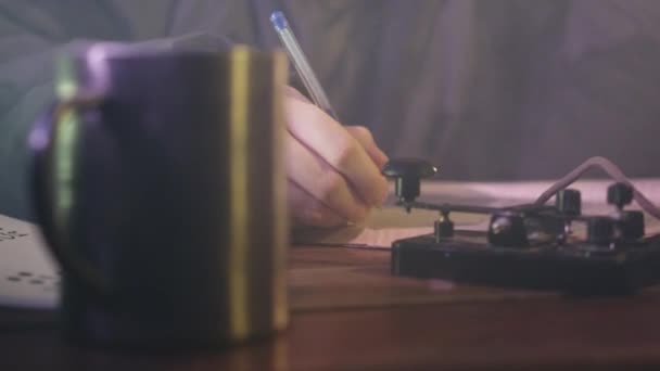 人的手是用笔写在日记上 用电报点击的 当茶水在杯子中冷却时 书写者用摩尔斯码传送信息 — 图库视频影像