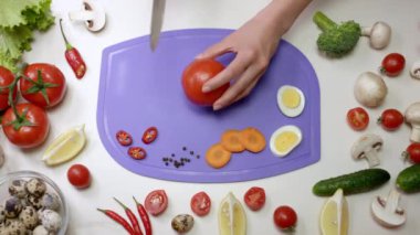 Ev hanımı lezzetli sandviçler için domatesleri ikiye böler. Kadın sandviç malzemelerini doğrama tahtasında hazırlıyor.