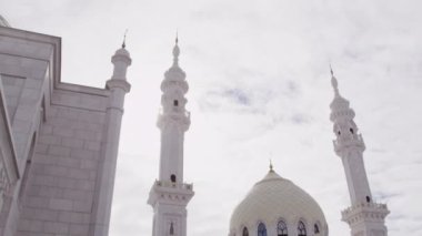 Gökyüzündeki büyük bulutları aşan güneş ışığıyla aydınlanan ünlü Beyaz Cami. Konum, zarif mimarisi ve binasıyla ziyaretçileri cezbediyor.