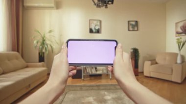 ALMATY, KAZAKHSTAN - 14 Eylül 2020: Kahverengi saçlı kadın akıllı telefondan ilginç ve heyecan verici videolar izliyor. Neşeli bayan kendi evinde video izlemekten hoşlanıyor.