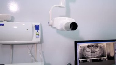 Dişçi, modern dijital röntgen cihazlarının yardımıyla bilgisayardaki hasta dişlerinin röntgen fotoğrafını inceliyor. Doktor sorunlu kısmın daha yakın resmini getiriyor.