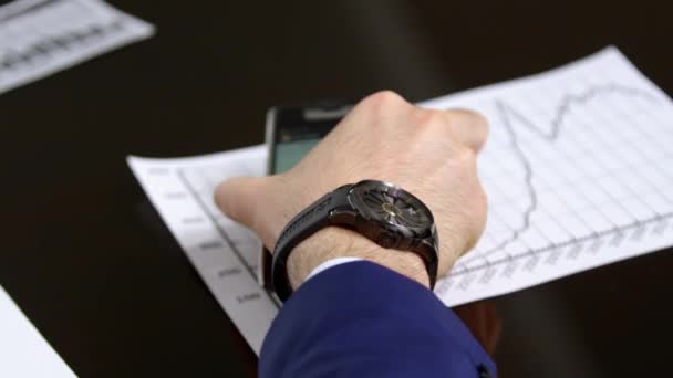 男はオフィスの会議テーブルの上に携帯電話を置きたいが 受信メッセージ作物の体を見てください マネージャは手に高価な時計を身に着けて — ストック動画