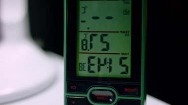 Modern elektronik saat akşam 9: 43 'ü gösteriyor. Masadaki dijital saat çalışma odasındaki sıcaklığı gösterir ve akşam kapanma zamanını gösterir