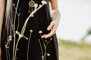 Elleri kır çiçeğine dokunan Boho kadını.