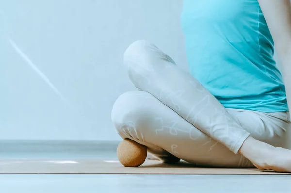 Woman doing yin yoga with cork ball on outer shin