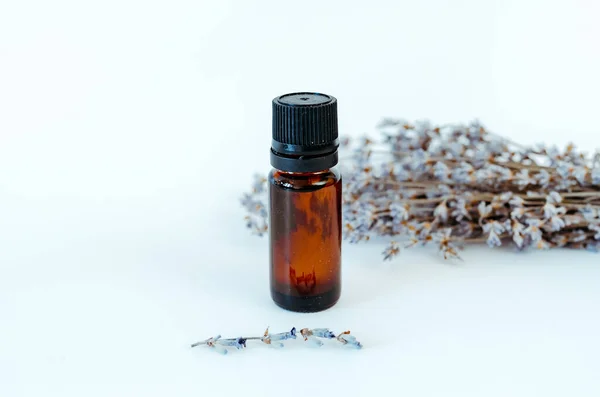 Small bottle of oil with lavender without label and lavender in the back on white background