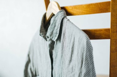 Sandalyede asılı gri çizgili keten gömleği kapat.