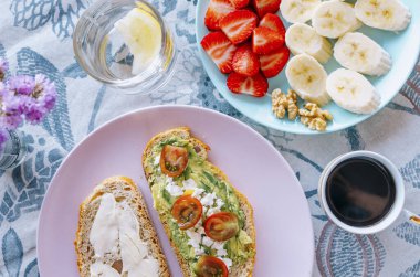 Avokado tostu, taze meyve ve kahve ile yayılmış canlı bir kahvaltı.
