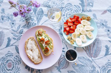 Taze meyve, tost ve çiçekli masa örtüsü üzerinde kahve ile güzel bir şekilde düzenlenmiş kahvaltı.