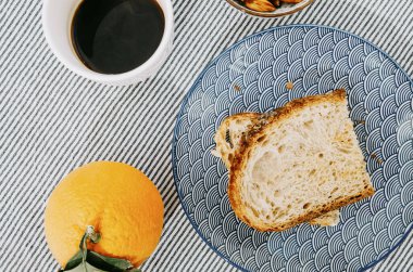 Ekmek, kahve ve portakallı basit kahvaltı manzarası.