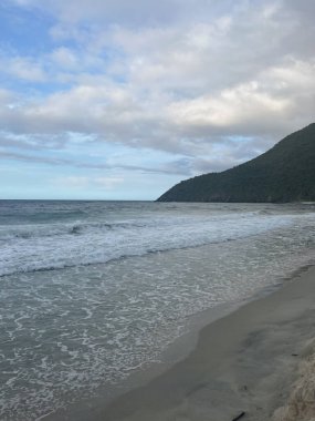  Kırık dalgalarla deniz manzarası, bulutlu gökyüzü doğal bir kıyı manzarası yaratıyor.