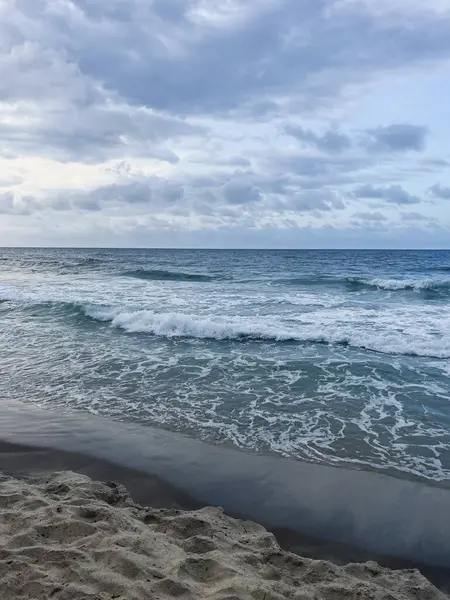  Kırık dalgalarla deniz manzarası, bulutlu gökyüzü doğal bir kıyı manzarası yaratıyor.
