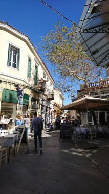 Atina, Yunanistan - 02 Nisan 2018: Turistlerin geçtiği ve yeniden dekore edilmekte olan bir dükkan açılmadan önce açık hava restoranlarıyla dolu kalabalık dar bir cadde