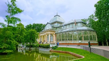 Palacio de Cristal del Retiro, Madrid, İspanya - 28 Mayıs 2018: Buen Retiro Parkı 'nda ağaçlar ve göletlerle çevrili kristal saray