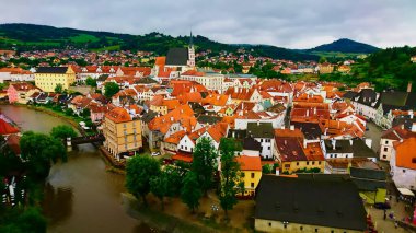 Cesky Krumlov, Çek Cumhuriyeti - 13 Haziran 2018: Bulutlu bir gökyüzünün altında kıvrık nehir ve dağlarla Cesky Krumlov 'un hava manzarası