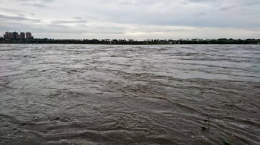 Jiang Kou Kasabası, Peng Shan Bölgesi, Mei Shan Şehri, Sichuan, Çin - 11 Temmuz 2018: Şiddetli yağmurun ardından aşırı su ile dolu bir nehir neredeyse nehir kıyısından gelen bulutlu gökyüzünün altında döşemeye neden oluyordu.