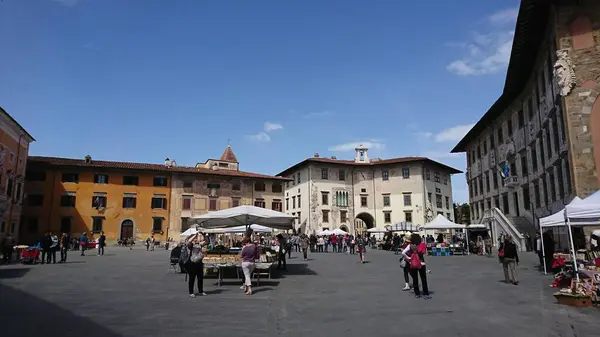 stock image Pisa, Italy - Apr 08 2018: A local market on Piazza dei Cavalieri, Knights Square, with tourists growing the stalls and Palazzo della Carovana on the side on a sunny spring day