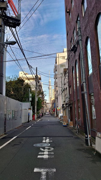 Tokyo, Japan - 10.26.2019: An ordinary Japanese street with shops alongside and Tokyo Skytree in the back