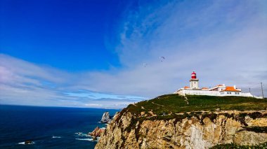 Cabo da Roca, Portugal - 06.03.2018: Cape Roca with a lighthouse overlooking the Atlantic Ocean and two parachutes clipart