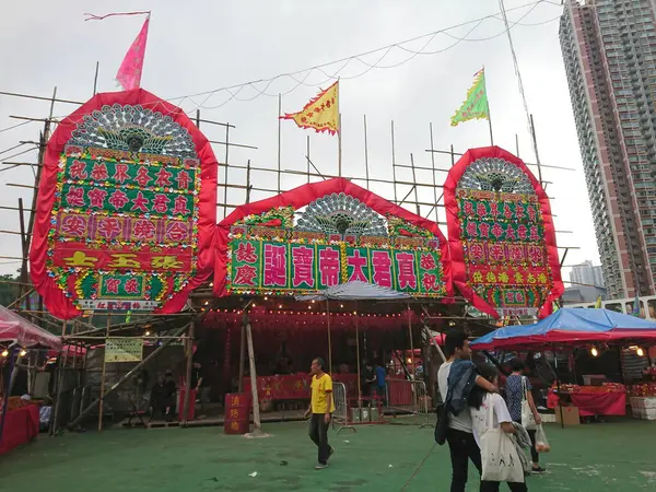 stock image Tsing Yi Bamboo Theatre, Tsing Yi, Hong Kong - April 18, 2019: Temporary temple of Zhen Jun celebrating his birth decorated by flower plagues and flags under a cloudy sky before the pandemic