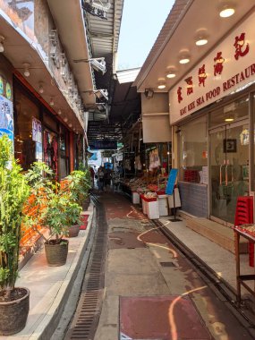 Hong Kong - 09.11.2021: Gündüz vakti Lau Fau Shan deniz ürünleri balıkçılığı köyünün boş bir sokaklarında, restoranların yanında ve kurutulmuş gıda dükkanlarında yürüyen birkaç yerli