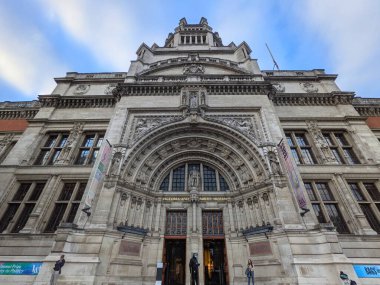 Londra, İngiltere - 10.15.2021: Cromwell Viktorya ve Albert Müzesi 'nin önündeki ön tarafta turistler dururken mavi gökyüzünün altındaki ön cepheye alçak açılı bakış