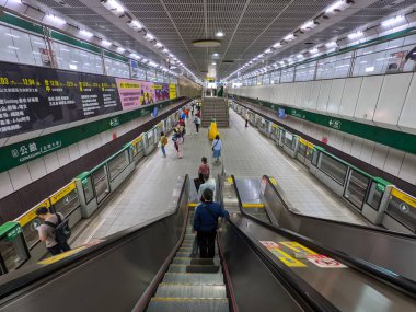 Taipei, Tayvan - 11.24.2022: Gongguan MRT İstasyonu 'ndaki salgın sırasında peron kapısında tren bekleyen yolcularla birlikte çift yönlü bir tren peronuna doğru yürüyen merdivenden bakın