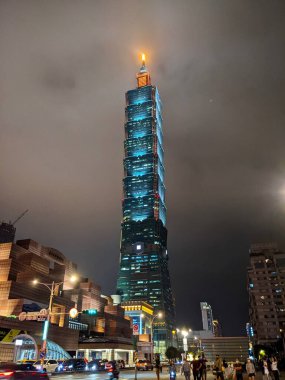 Taipei, Tayvan - 11.22.2022: Taipei Dünya Ticaret Merkezi ile aydınlatılmış Tapei 101 ve ön tarafta MRT çıkışı ve Xinyi Yolu 'ndaki yayalar gece sis sırasında