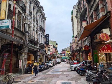 Taipei, Taiwan - 11.22.2022: Pedestrians walking on Dihua Street alongside dried goods shops and tea stores in traditional shophouses in Dadaocheng during the pandemic under a cloudy sky clipart