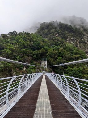 Taroko, Tayvan - 11.26.2022: Liwu Nehri üzerindeki boş simetrik Buluowan Kablo Askı Köprüsü yağmurlu bir günde salgın sırasında meydana gelen 403 depreminden önce dağlarda sis ile kaplı.