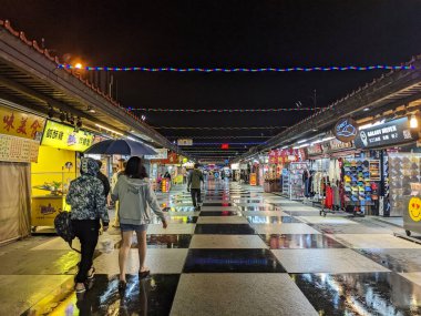 Hualien, Tayvan - 11.24.2022: Yağmurlu bir gecede salgın sırasında Hualien 'daki Dongdamen Gece Pazarı' ndaki marketlere göz atan birkaç müşteri