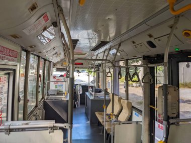 Tainan, Taiwan - 12.01.2022: An empty bus interior viewed from the back of the bus with a driver in the front heading to Anping District under sunlight during the pandemic clipart