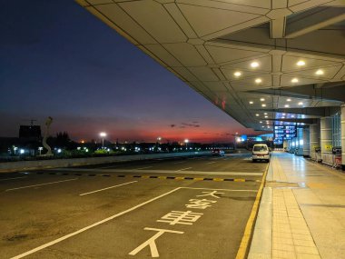 Kaohsiung, Tayvan - 12.02.2022: Salgın sırasında Kaohsiung Uluslararası Havalimanı 'nda gün batımında birkaç araçla uluslararası terminalin dışında neredeyse boş bir yol kenarı bırakma alanı