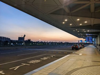 Kaohsiung, Tayvan - 12.02.2022: Salgın sırasında Kaohsiung Uluslararası Havalimanı 'nda gün batımında birkaç araçla uluslararası terminalin dışında neredeyse boş bir yol kenarı bırakma alanı