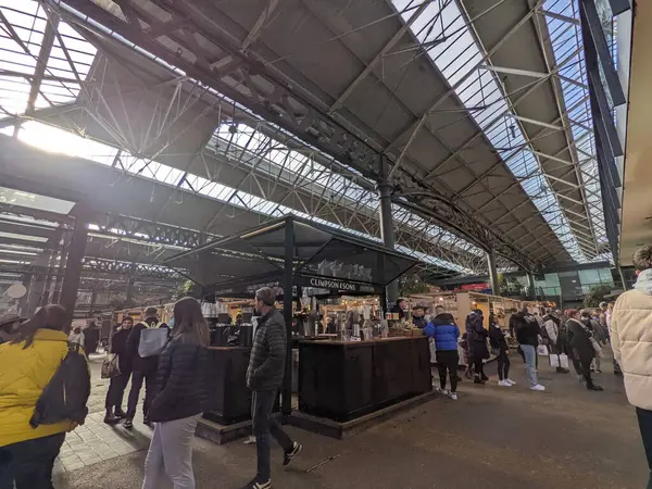 Londra, İngiltere - 02.05.2022: İnsanlar salgın sırasında cam çatı altında güneşli bir günde Old Spitalfields Market 'te kahve ve el sanatları tezgahlarına bakıyorlar