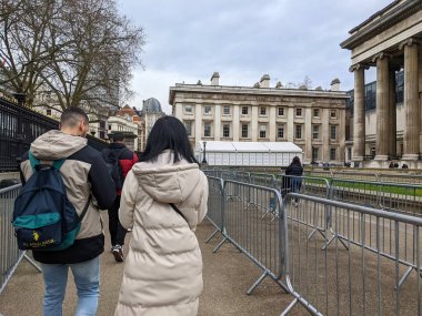 Londra, İngiltere - 03.11.2022: Bulutlu bir günde Britanya Müzesi 'nin avlusuna girmeden önce beyaz çadırdaki güvenlik kontrolünden geçmek için bariyerler arasında kuyruğa giren ziyaretçiler